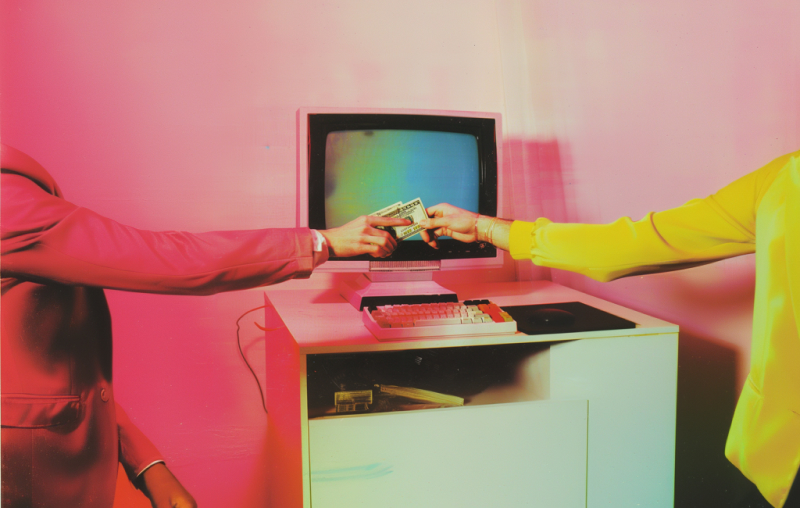 Surreal image featuring two people extending their arms from opposite sides, exchanging dollar bills in front of a retro computer. The computer, with a blank screen and an old keyboard, sits on a small desk. One person is dressed in a pink suit, while the other wears a yellow outfit, set against a vibrant pink and orange background.